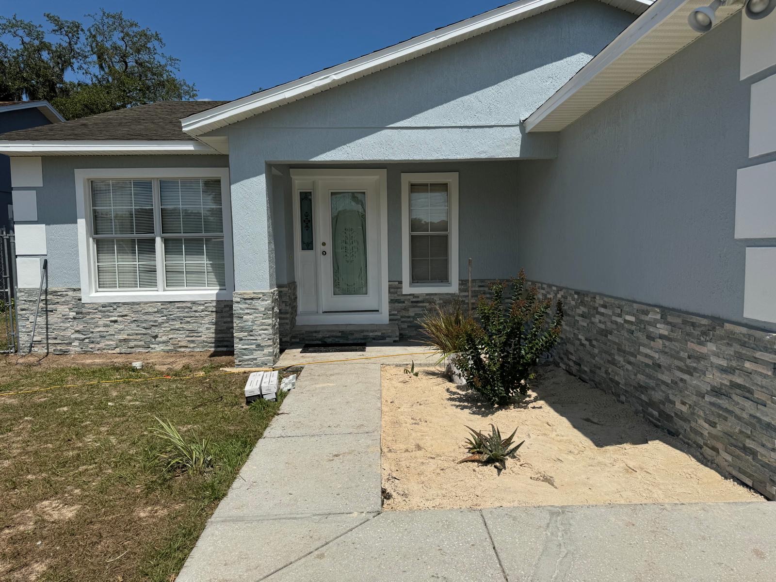 Freshly painted light blue Haines City home with new stacked stone veneer and white trim
