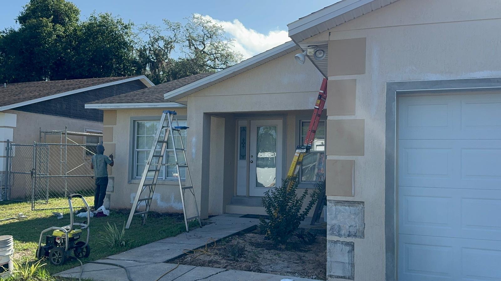 Maxter crew member painting the exterior stucco of a Florida home from a ladder